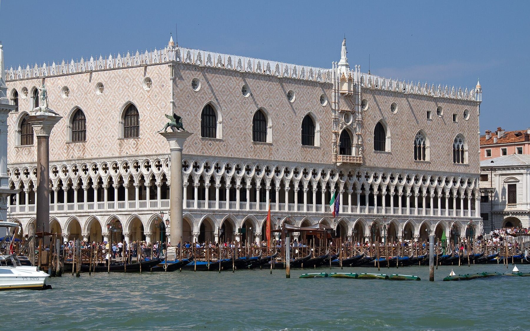 Gondolas moored in a row on the Bacino in front of the Piazzetta, mooring poles in the foreground