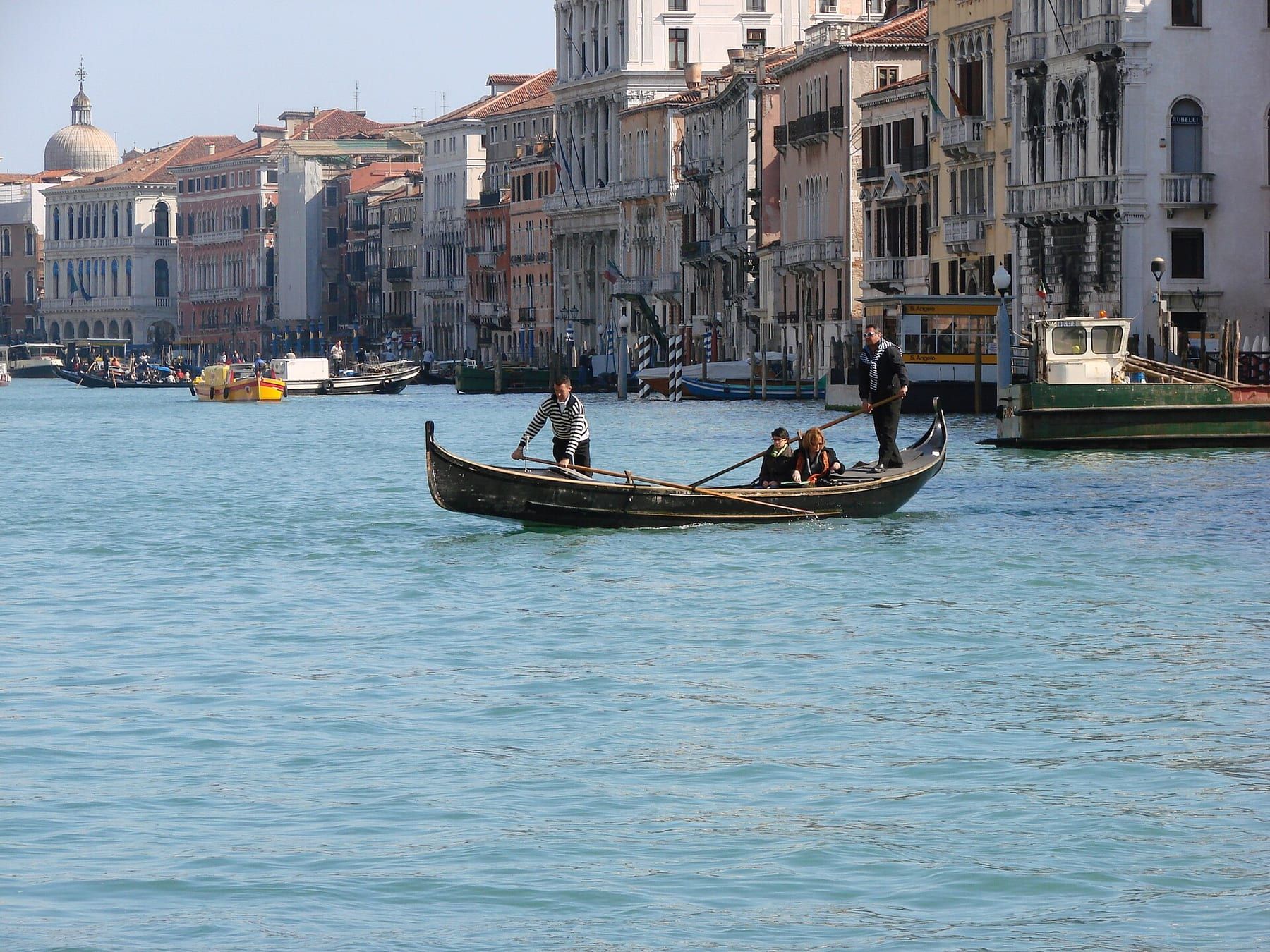 Passengers standing in a traghetto gondola crossing the Grand Canal near the Rialto market