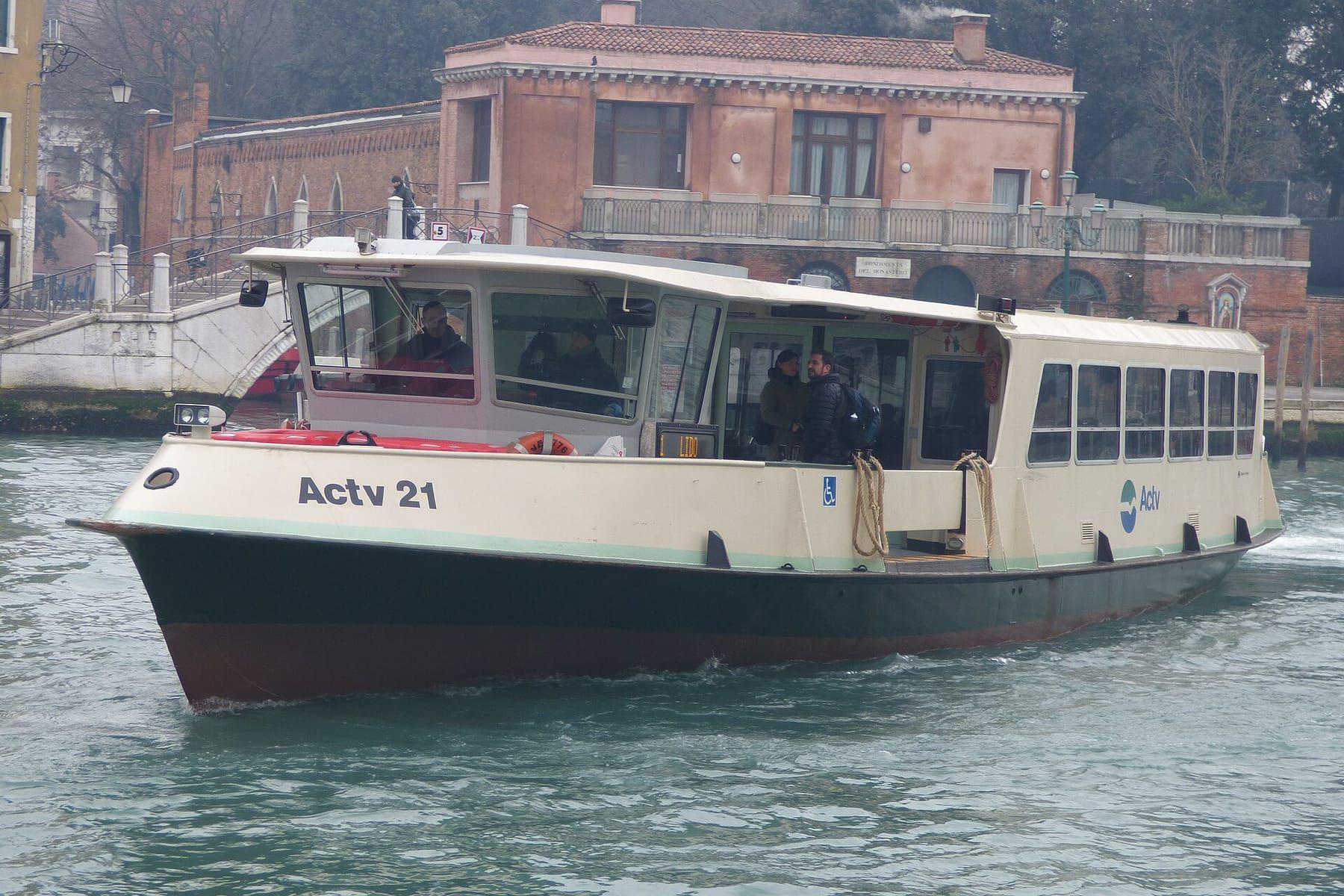 An ACTV vaporetto crossing the Grand Canal with passengers standing at the open stern rail